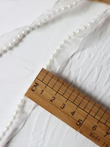Detail of white organza lace trim with 4mm pearl beads and measuring ruler view