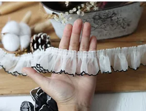 Macro detail of 4cm wide pleated white chiffon lace trim with black wavy edge for DIY crafts