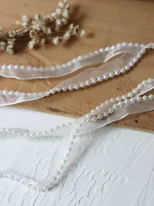 Detail of white organza ribbon with pearl bead trim for clothing decoration