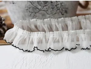 Close-up of 4cm white pleated chiffon lace trim with black wavy scalloped edges for DIY sewing