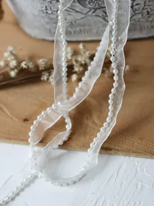 Detail of white organza lace trim with delicate pearls for dress and garment decoration