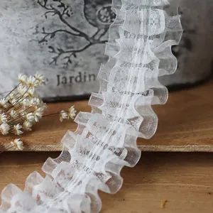 White double-layered pleated lace trim for Lolita sleeves and DIY crafts on a wooden surface