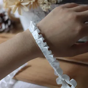 Detailed view of white pleated satin ribbon trim with delicate ruffles for DIY sewing