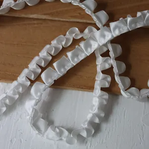 Close-up of white satin pleated ribbon lace trim for DIY doll dress sewing projects