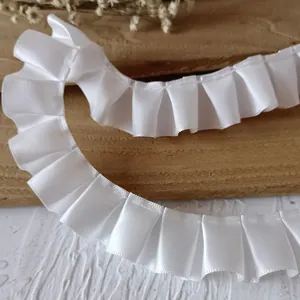 Macro detail of 2.5cm pleated white satin ribbon trim with smooth glossy texture for DIY