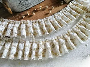 Close-up of pleated cream lace trim with golden floral patterns for DIY dress sewing