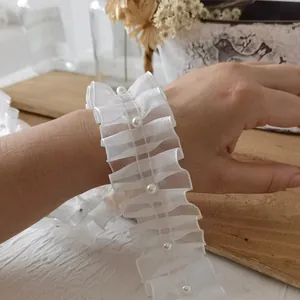 White organza ruffled lace wristband with elegant pearls on a wooden tabletop