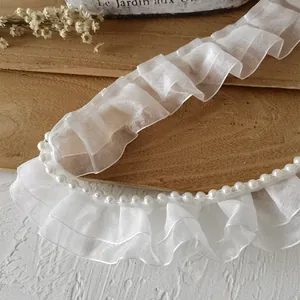 Detailaufnahme der zweilagigen weißen Organza-Plissee-Spitze mit Perlenverzierung