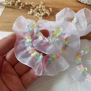 Macro shot of white organza scrunchie with colorful pastel plush trim detail