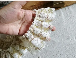 Detail of white pleated lace trim with gold embroidery for DIY clothing projects