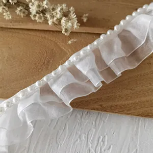 Nahaufnahme der weißen doppellagigen Falten-Organza-Spitze mit elegantem Perlenrand