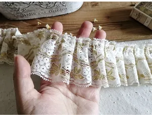 Macro detail of white pleated lace trim with gold leaf prints for Lolita dresses