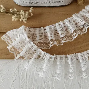 Détail de la bordure en dentelle blanche plissée à double couche avec motifs floraux