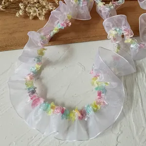 Detail of 2cm pleated white mesh lace trim with colorful floral tassels on wooden background