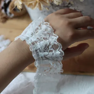 Detailed view of white pleated lace trim with scalloped edges used on a garment sleeve