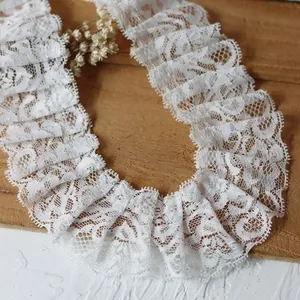 Close-up of pleated white lace trim with floral mesh texture on a wooden background
