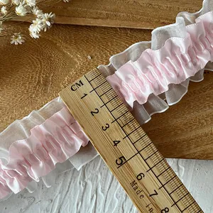 Bordo in pizzo elastico a doppio strato rosa e bianco con righello su base in legno
