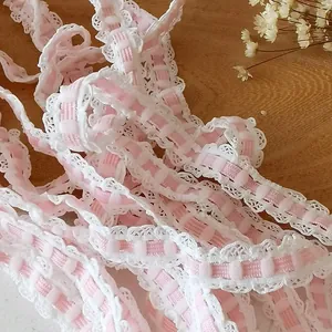 Pink checkered elastic lace trim with white ruffled edges on a rustic wooden background