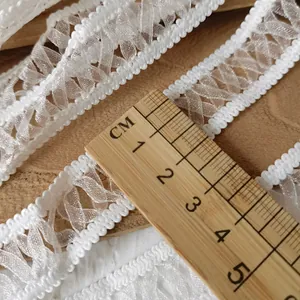 Detail of 3cm white elastic lace trim with scalloped edges and woven mesh texture
