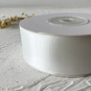 Gros plan sur un rouleau de ruban de satin blanc de 2,5 cm pour loisirs créatifs et DIY