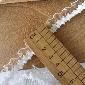 5m white pleated elastic lace trim with ruffled edge and scale ruler on wood background