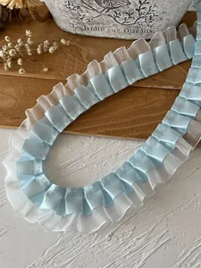 Close-up of pleated light blue satin ribbon and white organza lace trim for DIY sewing