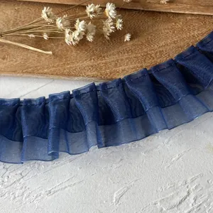 Close-up of dark navy pleated lace trim and organza ribbon on a wooden background