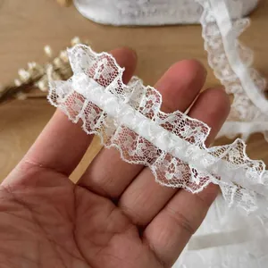 White ruffled lace trim ribbon for DIY sewing crafts and home decor on wooden background