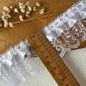 White pleated lace ribbon trim for DIY sewing crafts on wooden background with dried flowers