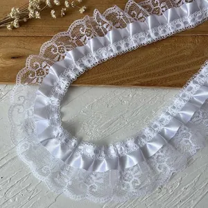 Detailed view of layered white lace trim with pleated satin ribbon for DIY sewing