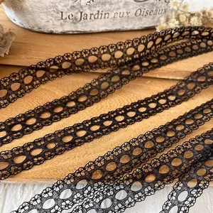 5m Black eyelash hollow lace ribbon with continuous circular mesh pattern on wood surface