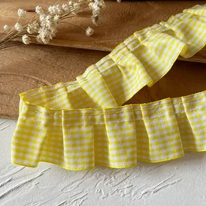 Detailed view of yellow gingham ruffled lace trim with fine white stitching for DIY