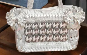 Detalle de bolsa Ita plateada con volantes de encaje, lazos de seda y ventana clara