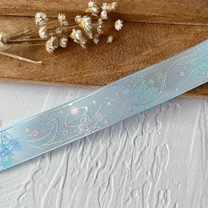 Dettaglio macro di nastro in mesh azzurro con farfalle e stampa olografica celeste