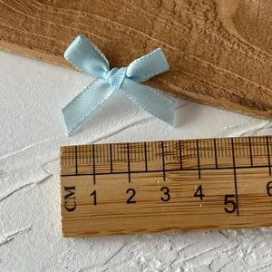 3cm light blue silk ribbon bow for DIY crafts shown with a wooden scale for sizing