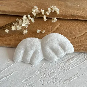 Close-up of white plush angel wings for DIY crafts on a natural wooden background