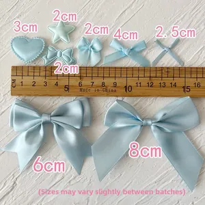 Light blue satin ribbon bows and heart charms shown with a ruler for size reference