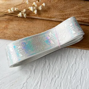Macro detail of laser holographic rose pattern on silver ribbon roll with pink fastener