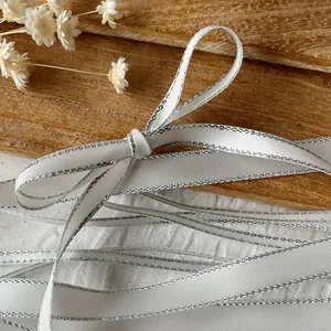 White satin ribbon with silver edges tied in a bow for DIY gift wrapping and crafts