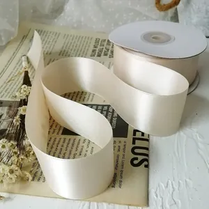 Detail of 4cm cream polyester satin ribbon roll with elegant silky texture and soft luster