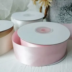 Detailed view of 4cm wide pink and white satin ribbons on spools for gift wrapping