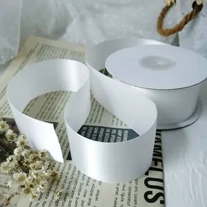 Close-up of 4cm wide white double-sided satin ribbon roll on elegant background