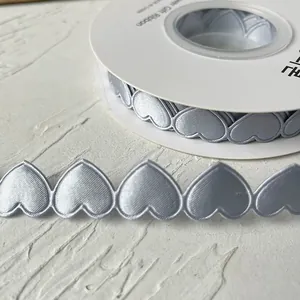 Macro shot of silver heart-shaped satin ribbon on white spool for DIY crafts