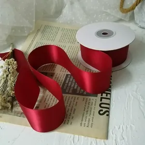 Detail of 4cm burgundy double-sided satin ribbon roll on vintage newspaper background