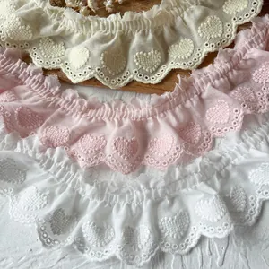 Detail of ruffled lace trim with heart embroidery in cream, pink, and white colors