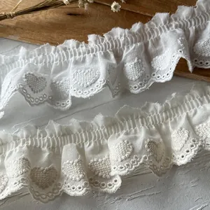 Macro detail of white heart embroidered cotton lace trim with ruffled edge and cutouts