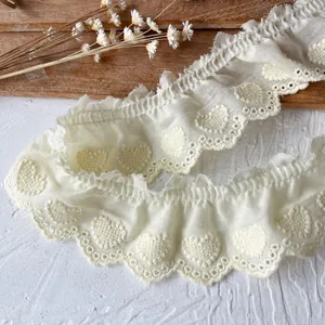 Macro detail of heart embroidery on cream cotton lace trim with scalloped edges