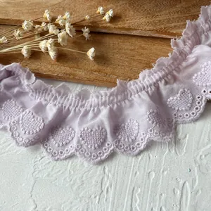 Close-up of light purple pleated cotton lace trim with embroidered heart patterns