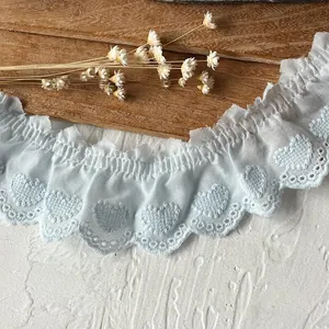 Macro detail of light blue pleated cotton lace trim with embroidered heart pattern