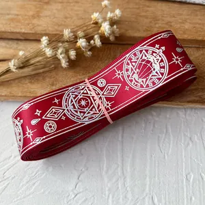 Close-up of deep red satin ribbon with white magic circle and star patterns for DIY crafts